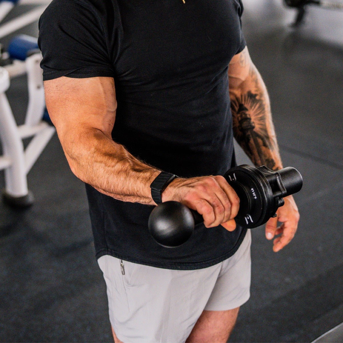 Tattooed athlete holding I-Bell showing forearm activation