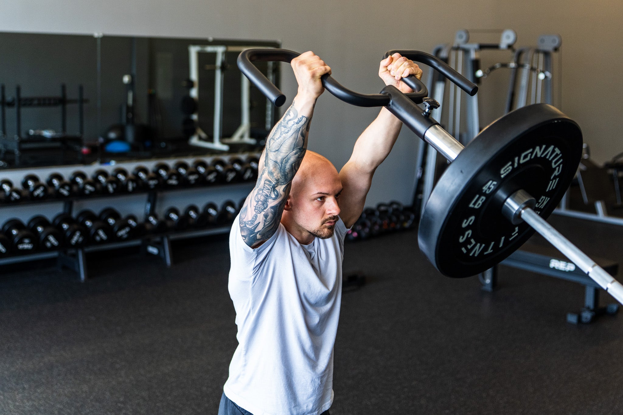 A lifter pressing the Viking Press overhead in a commercial gym